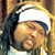 Pixelated static image of a person with dark hair wearing a white headband, set against warm-toned background elements.