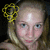A pixelated close-up of a person with light skin holding a yellow and black patterned object near their head against a dark background.