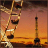 A Ferris wheel with illuminated cabins and the Eiffel Tower against an orange sunset sky.