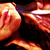 Pixelated close-up of a figure with light skin tones and red hair, wearing a white headband, against a dark background with orange and red hues.