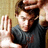 A pixelated image of a person with brown hair wearing a dark gray shirt, holding up three fingers against a light beige background.