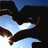 Animated sequence of dark silhouetted figures forming a heart shape against blue sky with white clouds, transitioning between frames.