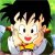 Pixelated cartoon character with spiky black hair, large black eyes, red mouth, yellow chest emblem, and white clothing against green background.