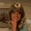 A woman with brown hair and a light blue top appears in a four- , her hand near her face, with a circular symbol above her head