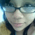 A person wearing glasses and a yellow garment appears in four -aligned with subtle facial expression changes
