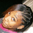 Pixelated close-up of a character's face with brown hair, light skin tone, and wide eyes against dark background.