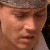 Pixelated close-up of a person's face with closed eyes, wearing a light brown cap and dark clothing, against a blurred background.