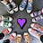 A static pixelated image with a central purple heart surrounded by a dark gray background and scattered colorful pixel clusters.