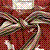 Pixelated static image with dense red and brown tones, featuring abstract shapes resembling a stylized face or mask with light-colored accents.