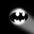 Black and white pixelated icon featuring a stylized bat symbol centered on a circular gradient background with light gray to white transition.