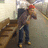 A person in a red cap and dark jacket stands on a staircase, holding a phone to their ear with one hand and a bag with the other.
