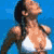 Pixelated static image of a woman in a white bikini top against a blue background, viewed from the side with long dark hair and visible shoulder straps.
