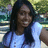 A pixelated static image shows a person with long dark hair wearing a light blue top against a blurred green and blue background.