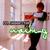 A person in a green-and-white raglan shirt and dark pants stands in a school hallway with windows and lockers, overlaid with text reading "I'LL NEVER STOP waiting" in green script.