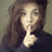 A pixelated static image shows a person with long brown hair holding a finger to their lips in a shushing gesture against a muted background.