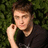 A pixelated image of a person with brown hair in a black shirt against green foliage, surrounded by blue text on yellow background.