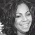 Pixelated grayscale image of a smiling person with closed eyes and dark hair against a dark background.