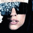 A pixelated close-up of a person's face with dark hair, sunglasses, and lips slightly parted in three showing mouth movement
