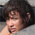 Pixelated close-up of a person with dark curly hair resting their head on a light surface, mouth slightly open, hand near face.