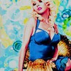 A woman with blonde hair in a blue halter dress poses against a colorful abstract background with swirling patterns.