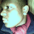 A pixelated image of a person in profile wearing a dark jacket with a pink inner collar, with partial text reading "Famous Tay" on a black background.