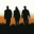 Three silhouetted figures stand against a gradient background transitioning from white to orange, with a dark horizontal band below them.