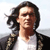 Static pixelated image of a person with long dark hair wearing a white shirt and dark jacket against light background.