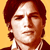 Pixelated static image of a person with brown hair against a yellow background, wearing a dark jacket and white shirt.