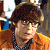 A pixelated contact sheet showing two frames of an animated icon featuring a character with brown hair and glasses on the left, next to green text reading "Original Icons .com" on a dark background.