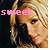 Pixelated image of a person with light brown hair and pink headband, wearing dark clothing against blurred background.