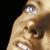Pixelated close-up of a person's face with light skin tone, visible eye and eyebrow details, and dark hair against a black background.