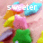 Animated sequence of colorful star-shaped objects with text changing from 'sweeter' to 'than' to 'sugar!' on a light pink background.