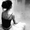 Black-and-white image of a woman in profile viewed from behind, wearing a dark sleeveless top with thin straps and light-colored bottoms.
