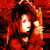 Pixelated red-toned image of a person with dark hair holding an orange object against a fiery background.