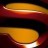 A pixelated abstract composition of horizontal bands in warm orange, red, and dark brown tones with a central rounded yellow-orange shape.