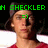Pixelated image of a person with brown hair wearing red clothing, green text above head reading 'N CHECKLER', and a green smiley face on the forehead.