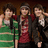 Three people stand together in a group photo on the left side of a red background, with pixelated text reading "it's cuteness to the 3rd power!!" and "xoxoxoxoxo love 'em!" below.