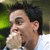 Pixelated static image of a person's face with dark hair and light skin, set against green foliage background.