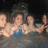 Pixelated image of four people in water with pink text labels on black background.