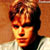 Pixelated static image of a person's face with warm-toned lighting and visible dithering effects on the background.