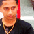 A person wearing a black shirt and gold chain necklace appears in a of four with slight variations in head position and background elements