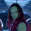 Pixelated static image of a person with long dark hair and greenish skin tone against blue background, likely from TV or movie character representation.