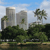 Pixelated landscape with two tall buildings, green trees, and a blue sky with clouds.