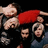 A static image shows multiple figures in a dynamic pose with one figure in a red top and others in dark clothing against a black background.