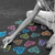 A pixelated static image shows a white figure with a long neck and head, surrounded by scattered colorful shapes on a dark background.
