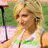 Pixelated image of a person with light brown hair wearing a white top, standing near a microphone against green and pink background elements.