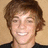 Pixelated portrait of a smiling person with brown hair against a beige background, with pink text labels and a number on a black field.