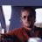 Pixelated static image of a person in sunglasses and red clothing against a dark blue background with white vertical elements on both sides.