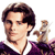 Pixelated image of a person with dark brown hair wearing a dark purple garment with white collar, holding a golden trophy-like object against a white background.