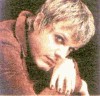 A person with short light brown hair wears a brown jacket over a dark shirt, shown in five sequential poses against a dark background.